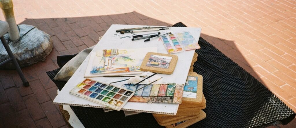 Art supplies including watercolors, brushes, and sketchpads laid out.